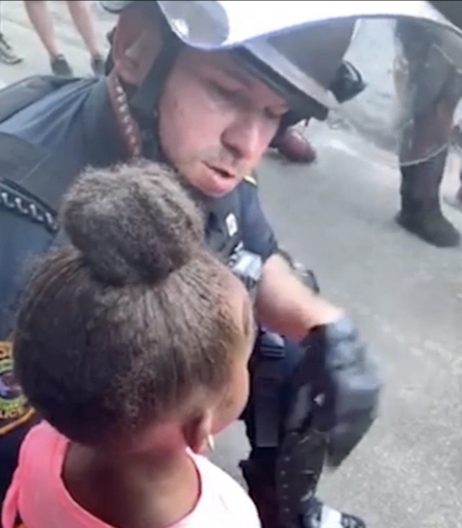 “Mi sparerai?”: una bimba impaurita consolata da un poliziotto durante le rivolte contro il razzismo negli USA